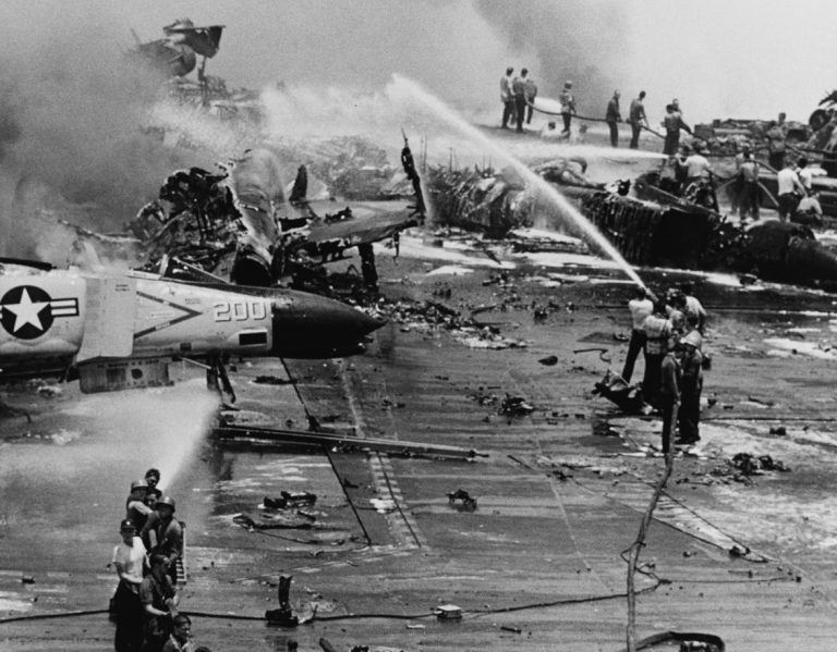 The deck and aircraft are on fire during the July 1967 disaster.