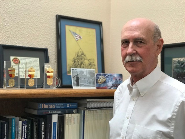 Richard standing next to mementos from his service.