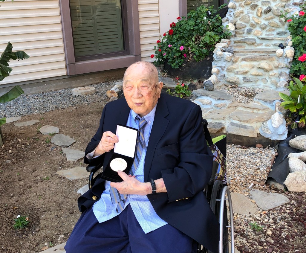 Wellington Yee Kwan holding the medal.