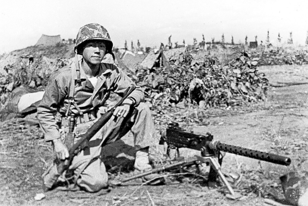 Lee in combat fatigues beside a machine gun in Korea.