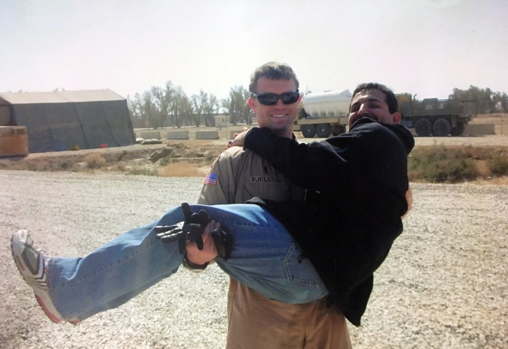 An American solder, Josh Fjelstad carries interpreter Khaleel Yasir in his arms.