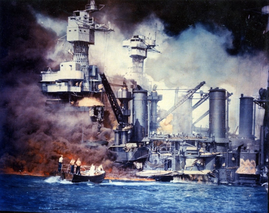 Sailors in a motor launch rescue a survivor from the water alongside the sunken USS West Virginia shortly after the Japanese air raid on Pearl Harbor.