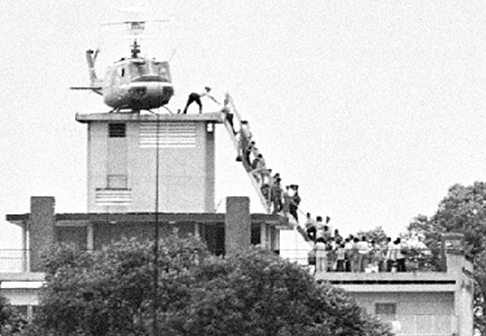 CIA officer helps evacuees up a rooftop ladder onto an American helicopter on 29 April 1975.