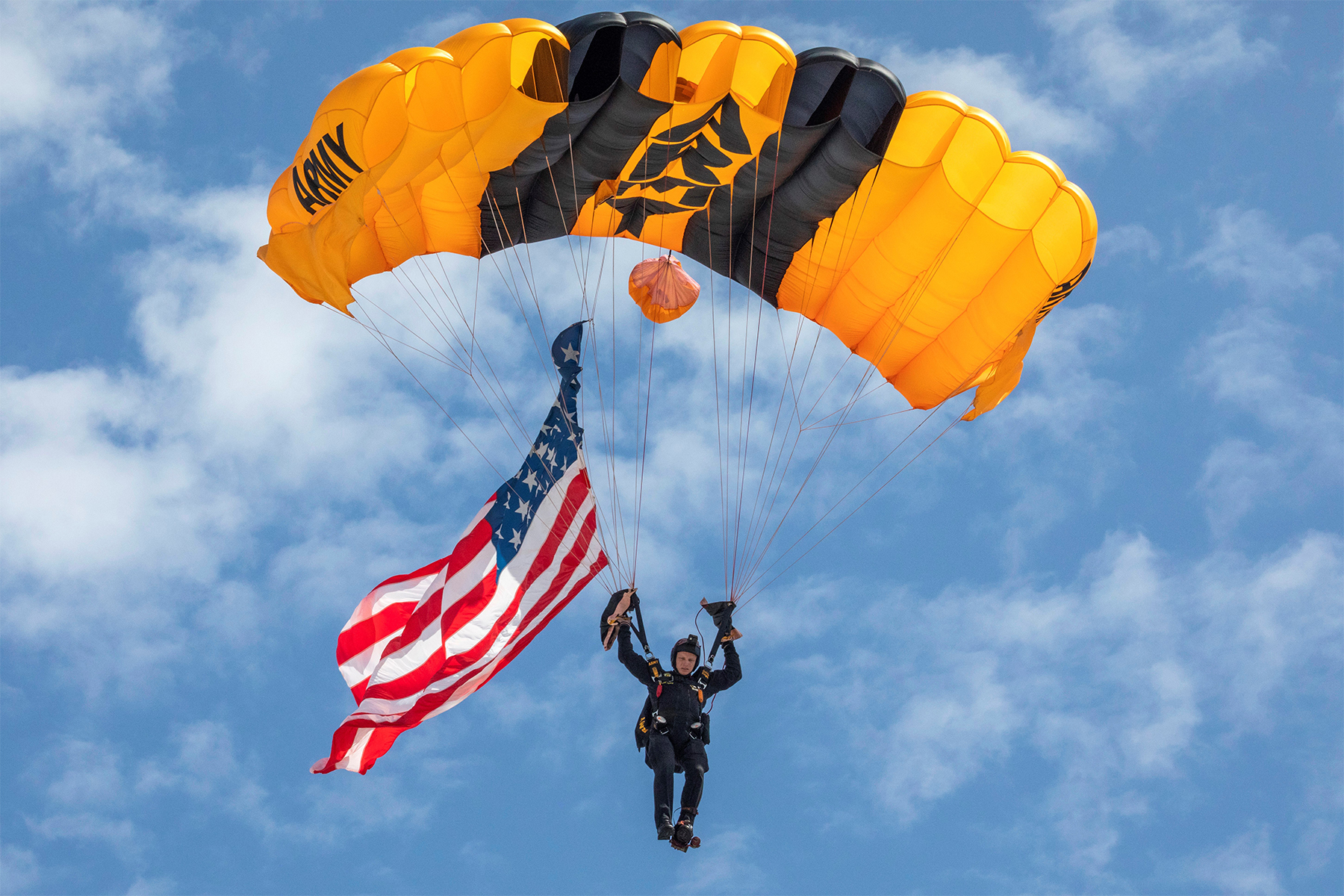 A member of the U.S. Army parachute team, the Golden Knights, delivers an American flag.