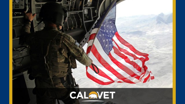 U.S. Army Sgt. Michael Misheff flies the American flag from the back of a CH-47 Chinook helicopter over southern Kandahar province.