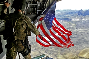 U.S. Army Sgt. Michael Misheff flies the American flag from the back of a CH-47 Chinook helicopter over southern Kandahar province, Afghanistan.