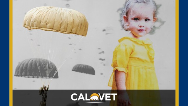 A toddler wearing a yellow dress made from the fabric of a WWII parachute.