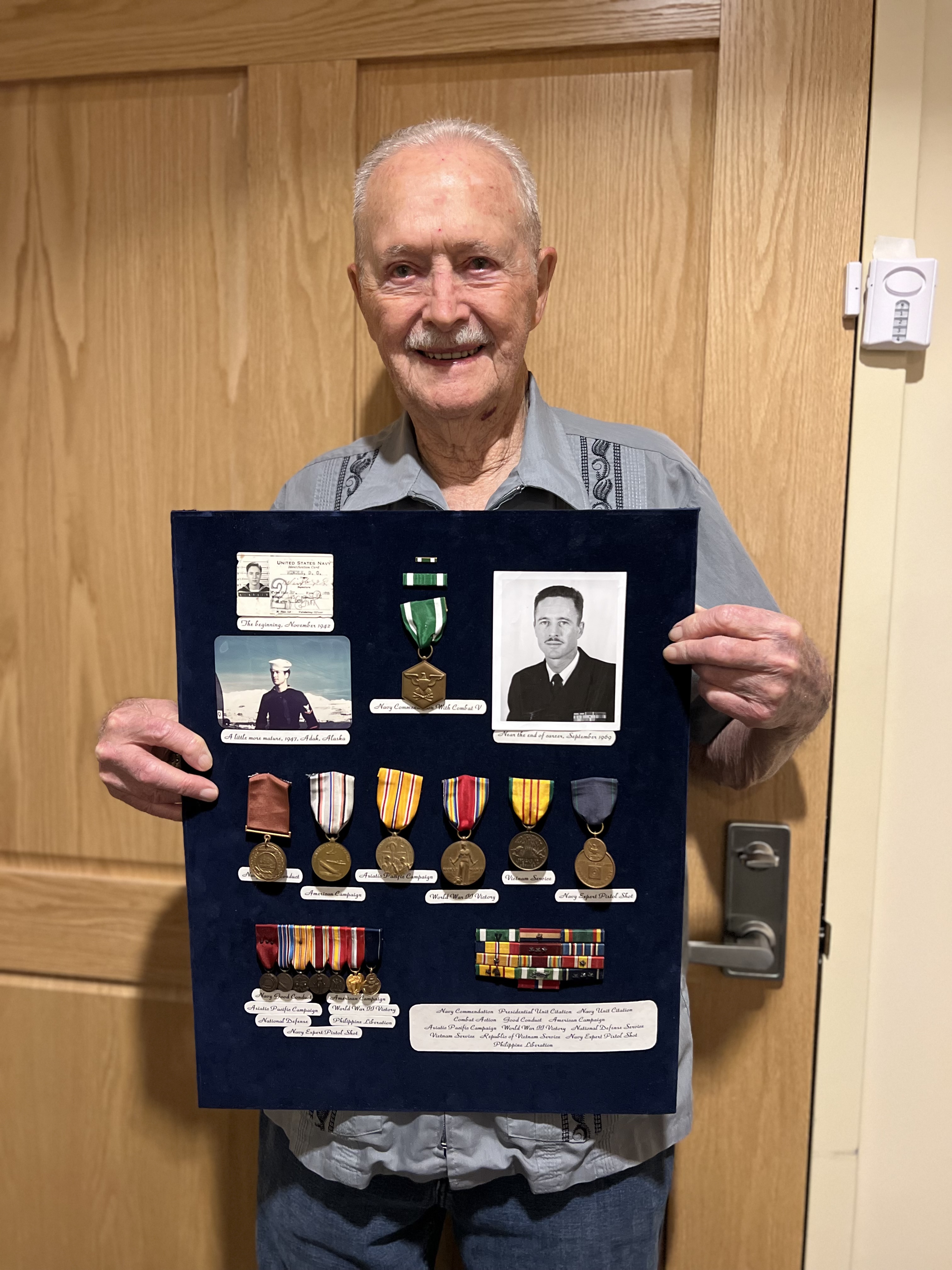 Photo of Don Windle holding memorabilia.