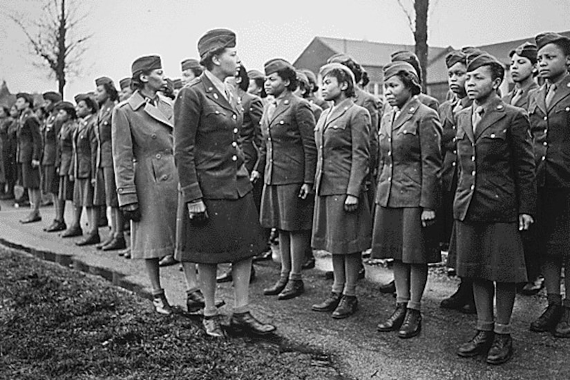 Women in military uniform in formation being addressed by an officer..