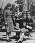 Women in military uniform outside near a tree.