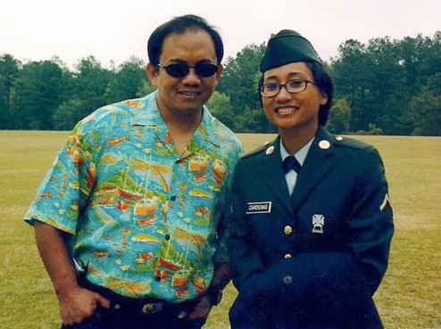 Servicemember in Army uniform standing next to man.