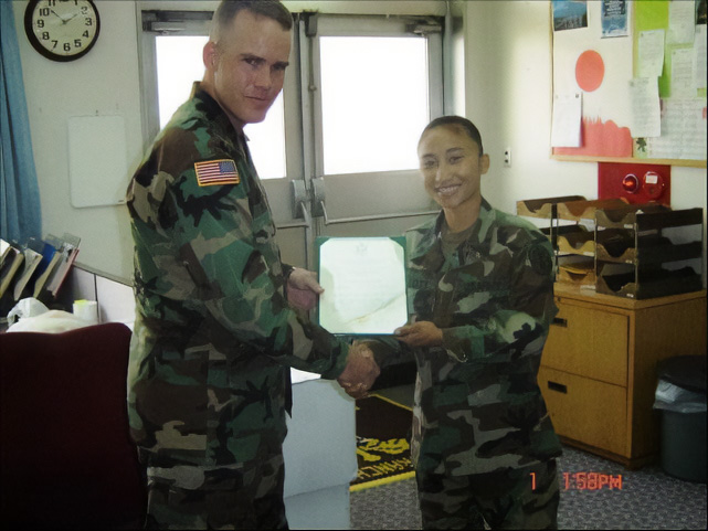Woman in U.S. Army uniform accepts certificate award from male soldier.