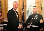 President Bill Clinton in the White House Oval Office with Marine officer.