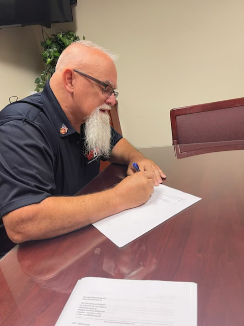 Man sitting at table signing paperwork.