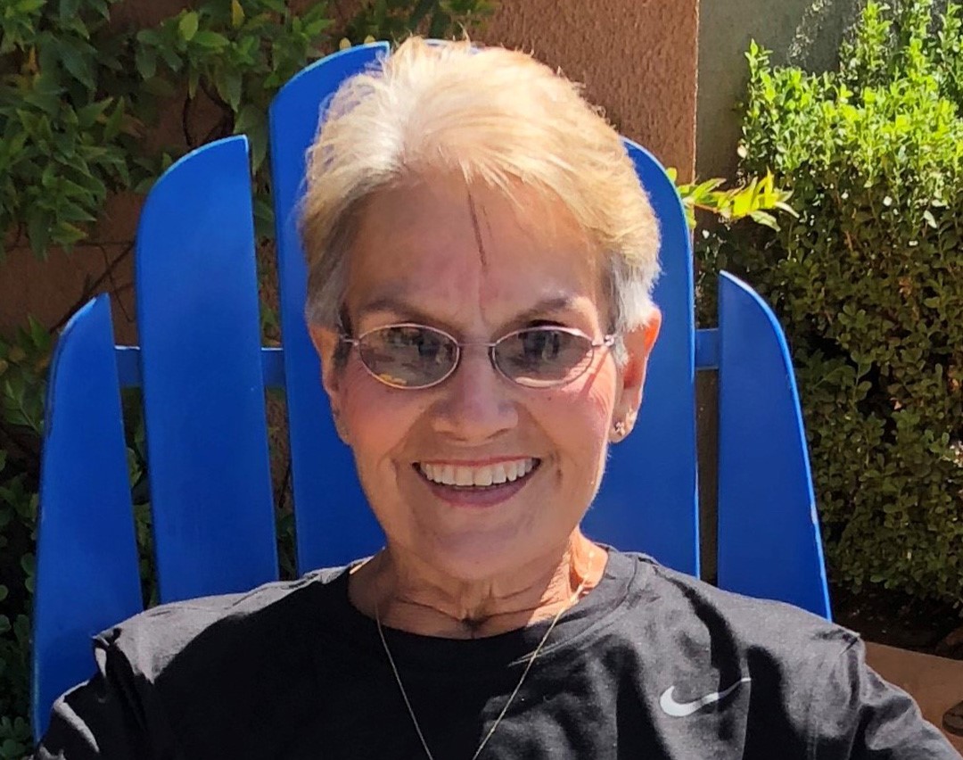Smiling woman outside on a blue chair.