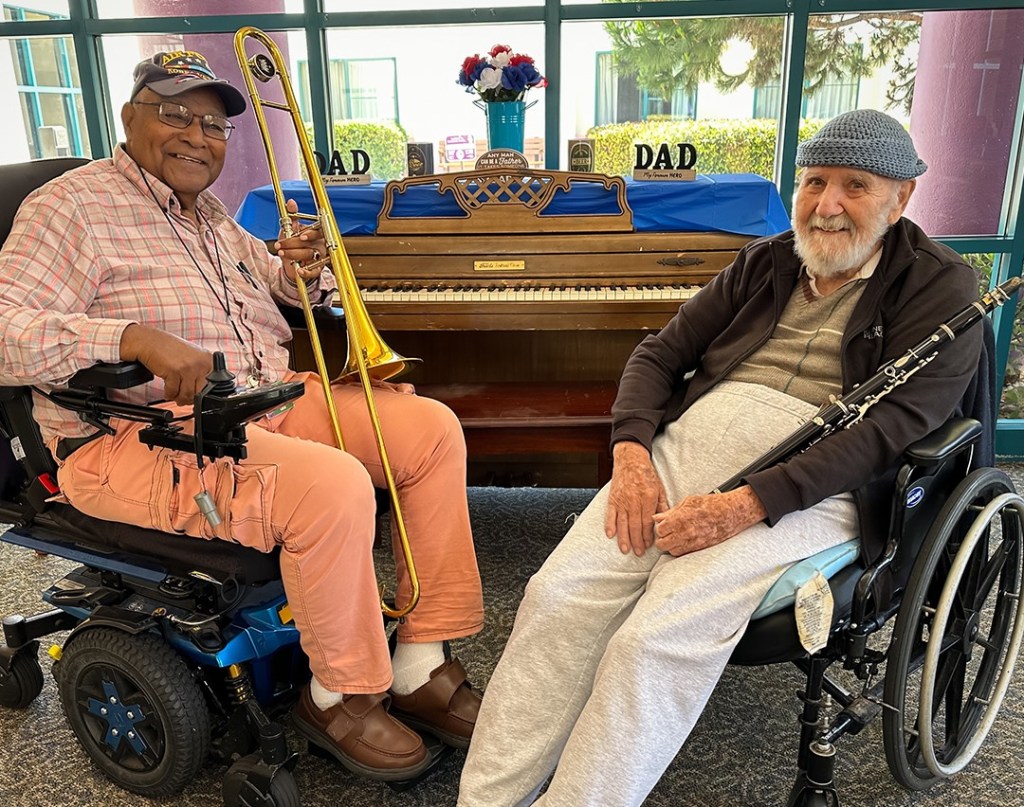 Two veterans in front of a piano, one holding a trombone and the other a clarinet.