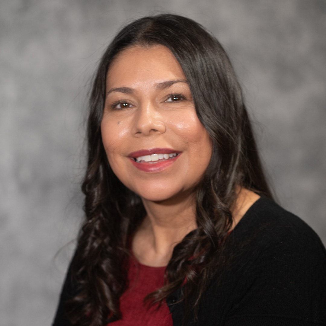 Smiling woman in front of gray background.